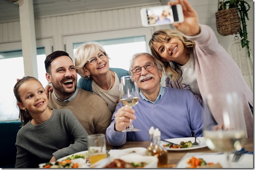 Below view of cheerful multi-generation family taking selfie in dining room. 