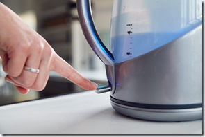 Close Up Of Woman Pressing Power Switch On Electric Kettle To Save Energy At Home